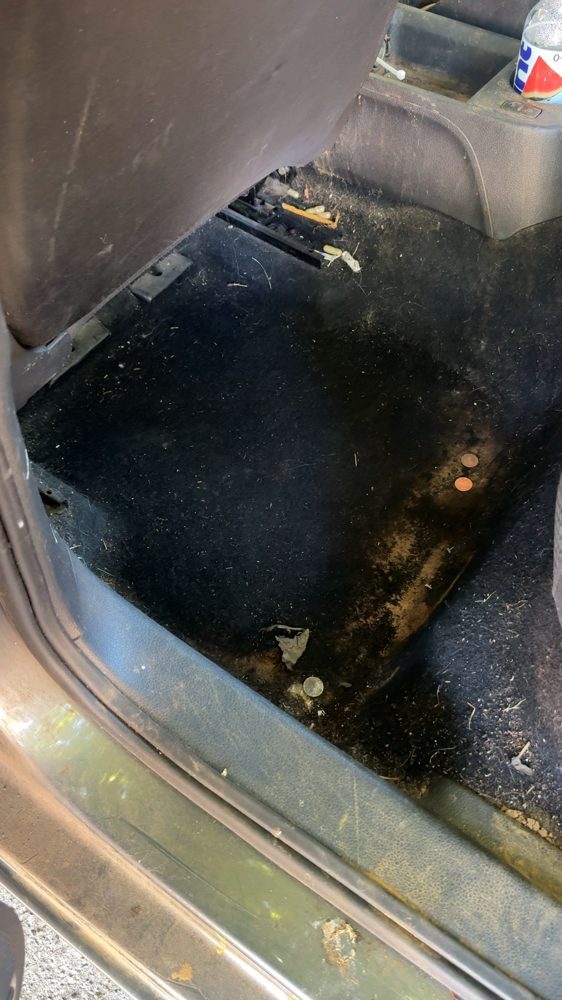 Dirty rear floor carpet of a Volkswagen before cleaning